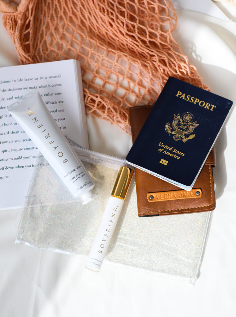 Hand and Body Creme and 8ml Eau de Parfum scattered alongside passport, book and wallet.